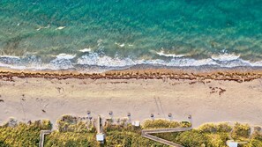 Vue aérienne d’une plage où l’on distingue clairement la ligne de rivage, un espace de stationnement et un chemin menant à la plage.