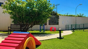 A playground with a slide, climbing structure, and a bench. - Nautilus Ap Vista Mar (Penha)