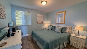 A bedroom with a bed, two bedside tables, a nightstand, a ceiling light, and a window with blinds. - Apollo 702: Updated Beach Front Condo! (Marco Island)