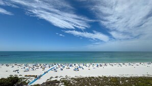 Une plage avec une vaste étendue de sable, un ciel bleu dégagé et une mer calme.