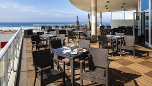 A deck with tables and chairs, overlooking the ocean. - Praia del Rey 3 Bedroom Villa (Obidos)