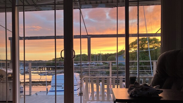A room with a large window overlooking a marina with boats and docks.