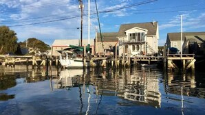 A waterfront property with a dock, a boat, and a house with a balcony.