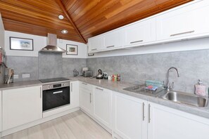 A modern kitchen with white cabinets, a stainless steel sink, and a built-in oven.