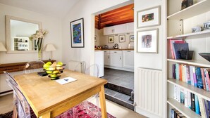 A modern kitchen with white cabinets, a wooden countertop, and a dining area with a wooden table and chairs. - GuestReady - Peaceful 2BR near Holyrood Park (Edinburgh)