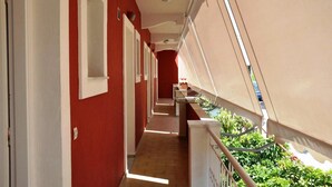 A corridor with red walls, white doors, and a balcony with a view of greenery.
