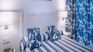 A hotel room with a bed, striped bedding, a telephone, and a nightstand. - Hotel Tahiti Playa and Suites (Santa Susanna)
