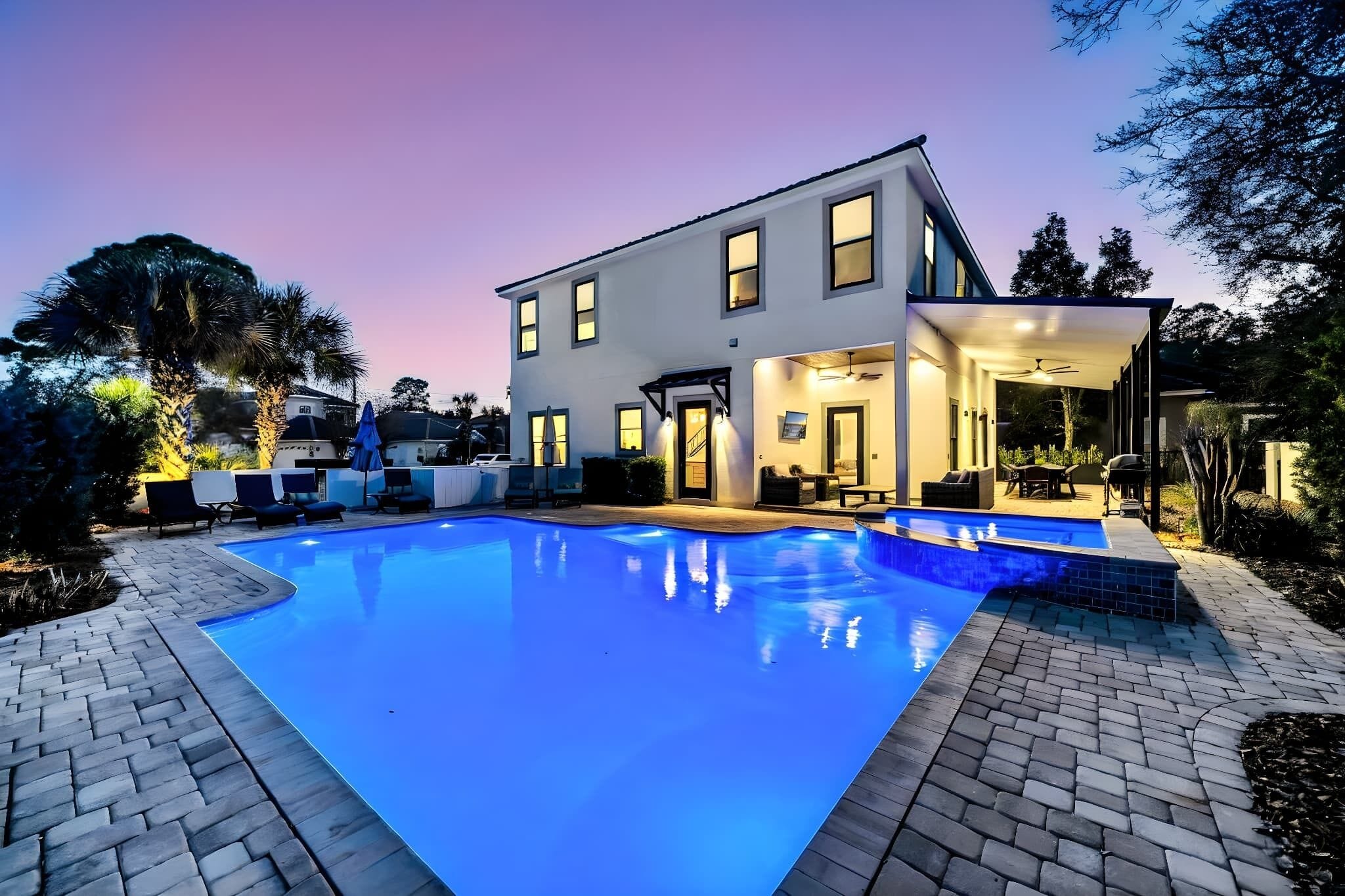 Une maison moderne à deux étages, dotée d’une piscine, d’un espace salon extérieur et d’un patio couvert.
