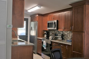 A modern kitchen with wooden cabinets, stainless steel appliances, and a tiled backsplash.