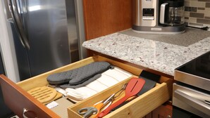 Une cuisine équipée d’un réfrigérateur en acier inoxydable, d’une machine à café et d’un tiroir contenant des ustensiles de cuisine.