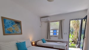 Hotellihuone, jossa on kaksi sänkyä, kattotuuletin, ilmastointilaite, ikkuna verhoilla ja näkymä ulos.