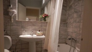 Un baño con lavamanos pedestal, espejo, ducha e inodoro.