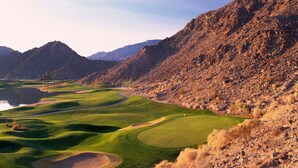 Un parcours de golf avec un lac, entouré de montagnes.