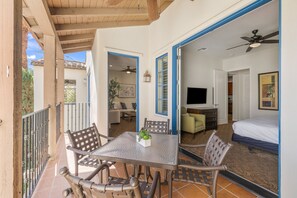 Una habitación con cama, televisión y zona de comedor con sillas y mesa.