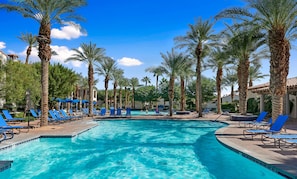 A swimming pool with blue lounge chairs and palm trees. - Deluxe King Casita, Pet Friendly! - (L76-B) (La Quinta)