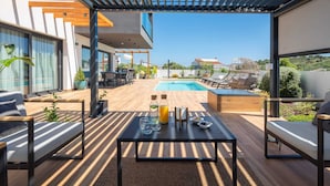 A modern outdoor seating area with a pool, wooden flooring, and a view of the pool and surrounding landscape. - Luxury Villa Silvery with Pool (Kanica)