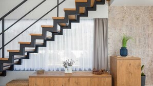 A modern living room with a wooden staircase, a wooden cabinet, and a potted plant. - Luxury Villa Silvery with Pool (Kanica)