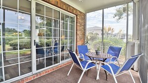 Un patio cubierto con pared de ladrillo, puertas correderas de vidrio y una mesa con sillas.