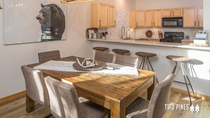 A modern kitchen with wooden cabinets, a central island, and a dining area with a wooden table and chairs.