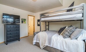 A bunk bed with a television on a dresser, a door, and a wall with a picture. - Adorable Townhome! 15 Min Drive to Resort! 5 Min Walk to Town Center and Shuttle (Big Sky)