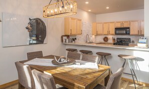 Une cuisine moderne avec des meubles en bois, un îlot central et un coin repas comprenant une table et des chaises en bois.