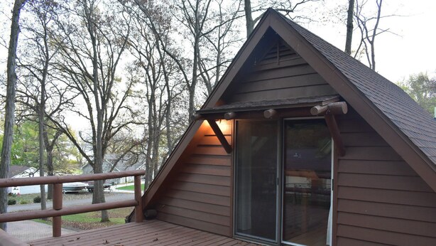 Une petite cabane dotée d’une terrasse en bois et d’une porte en verre.