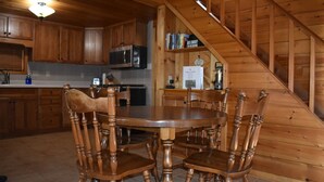 Un intérieur en bois comprenant une table et des chaises, un coin cuisine et un escalier.