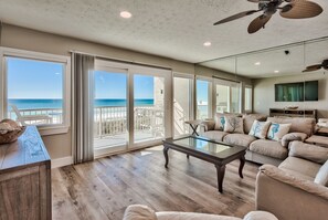 A spacious living room with a large glass table, a beige sofa set, and a view of the ocean through large sliding glass doors. - Renovated Low Density Beach Front With Private Beach (Destin)