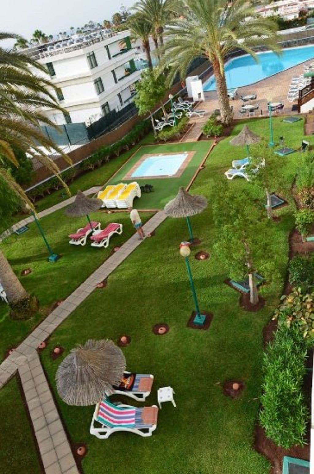 A pool area with sun loungers, umbrellas, and a small pool.