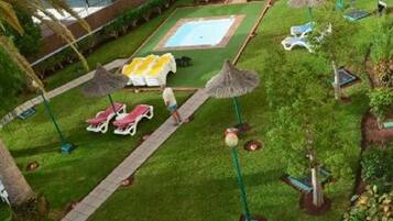 A pool area with sun loungers, umbrellas, and a small pool.