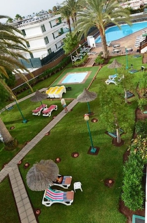 Zona de piscina con tumbonas, sombrillas y una piscina pequeña.