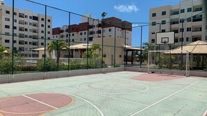 Een basketbalveld buiten, omheind door gebouwen.