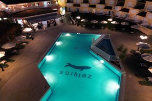 A swimming pool with a dolphin logo, surrounded by lounge chairs and umbrellas.