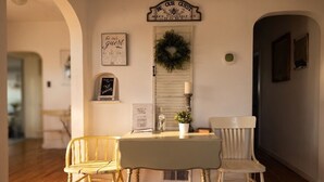 A dining area with a table and two chairs, a sign above the door, and a wreath on the door. - Restored 1920s Corner Cottage – Bryce Gateway Retreat (Panguitch)