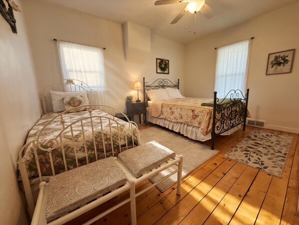 A bedroom with two beds, a ceiling fan, and a window with curtains.