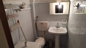 A compact bathroom with a toilet, sink, and washing machine.