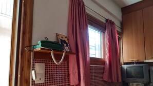 A kitchen with wooden cabinets, a microwave, and a television.