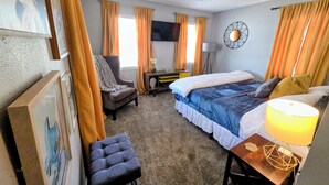 Une chambre d’hôtel équipée d’un lit, d’une chaise, d’un bureau, d’une télévision et d’un ventilateur de plafond.