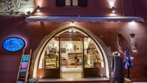 A boutique hotel entrance with an arched doorway, a neon sign, and a display of local crafts outside. - Veneto Boutique Hotel (Rethymno)