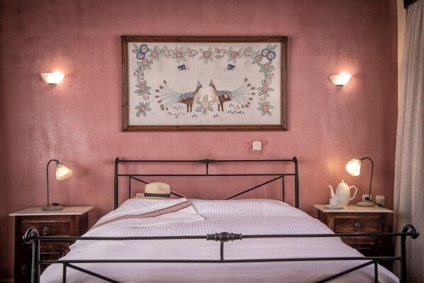 A bed with a metal frame, two bedside tables with lamps, a framed picture above the bed, and a wall-mounted light fixture. - Veneto Boutique Hotel (Rethymno)