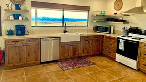 Una cocina con armarios de madera, lavavajillas, estufa, microondas y ventana con vista a las montañas.