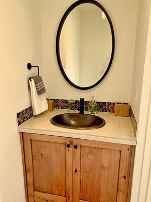 Ein Badezimmer mit einem Holzbadschrank, einem runden Spiegel und einem Waschbecken.