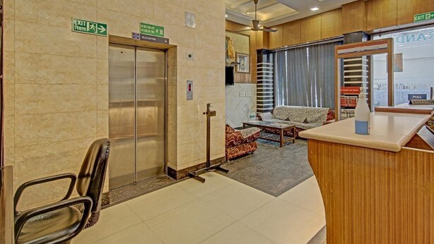 A hotel lobby with an elevator, reception desk, and seating area. - The Le Grand (New Delhi)