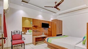 A modern hotel room with a bed, a desk, a chair, and a TV. - The Le Grand (New Delhi)