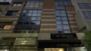 A building with a sign for 'The Le Grand Guest House' and 'Modern Trading Corporation' on the ground floor. - The Le Grand (New Delhi)