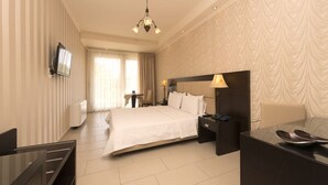 A hotel room with a large bed, bedside tables, a desk, and a television on the wall. - Ocean View (Pangaio)