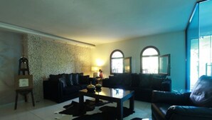 A living room with a stone wall, two sofas, a coffee table, and a cowhide rug. - Ocean View (Pangaio)