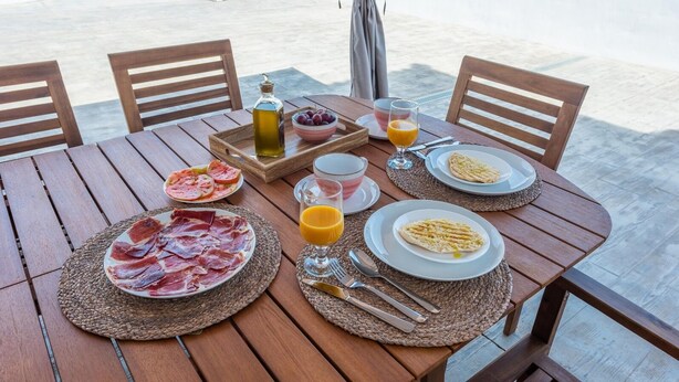 A wooden table set with plates of food, a bottle of olive oil, a bowl of cherries, and a glass of orange juice. - Casa Mari de Almogía by Ruralidays (Málaga)