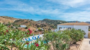 A pool area with blue lounge chairs, a white building with a tiled roof, and a hilly landscape in the background. - Casa Mari de Almogía by Ruralidays (Málaga)
