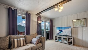 Een gezellige woonkamer met een bank, een televisie en uitzicht op een besneeuwd landschap.